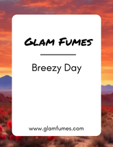 A product label for 'Breezy Day' home diffuser oil and linen spray by Glam Fumes, featuring a scenic background with a sunset and desert landscape.